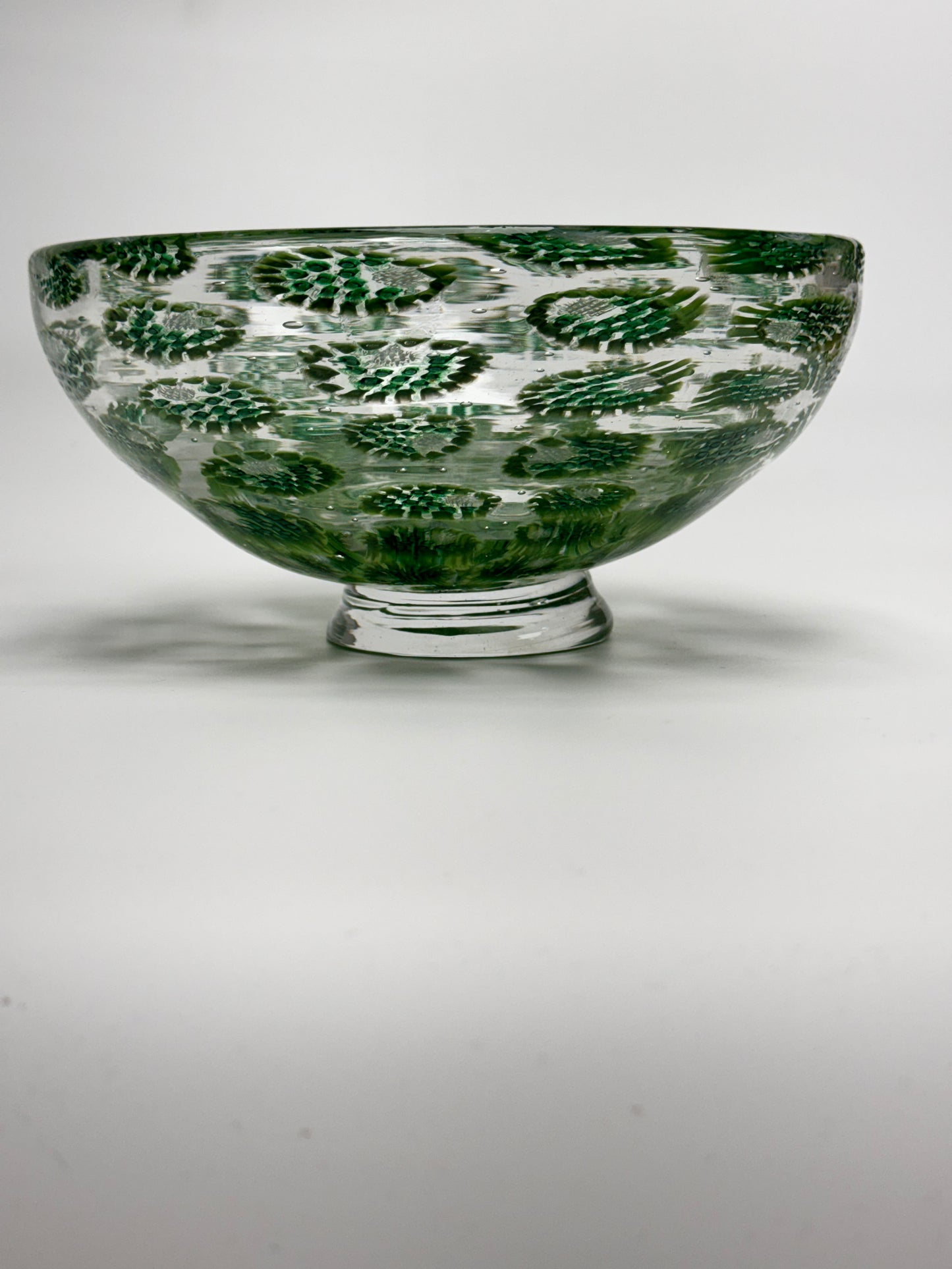 Decorative glass bowl with green and white pattern on a white background